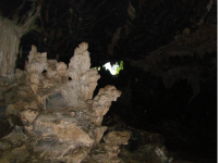Foto junto à entrada da caverna, onde a claridade incide sobre enormes estalactites, formando um belo e curioso cenário.
