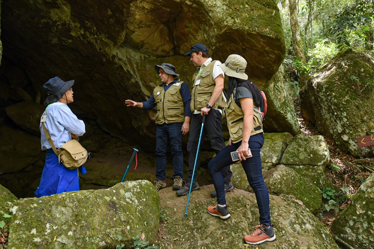 Representantes da UNESCO com o coordenador científico do geoparque, geólogo André Borba, na “Caverna da Escuridão”, durante o trajeto da trilha na Pedra do Segredo. Estas grutas são comuns na região, esculpidas pela passagem das águas subterrâneas