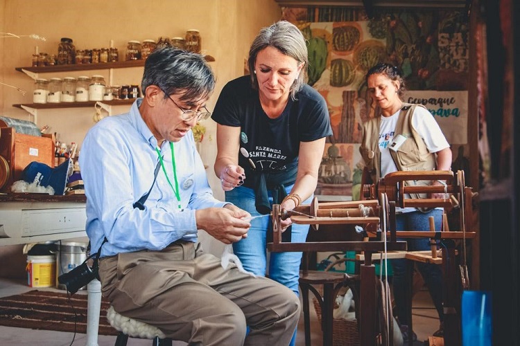 Avaliador Watanabe experimenta a fiação de lã.  Crédito da Foto: Catherine Vargas, Assessoria de Comunicação da Prefeitura de Caçapava do Sul