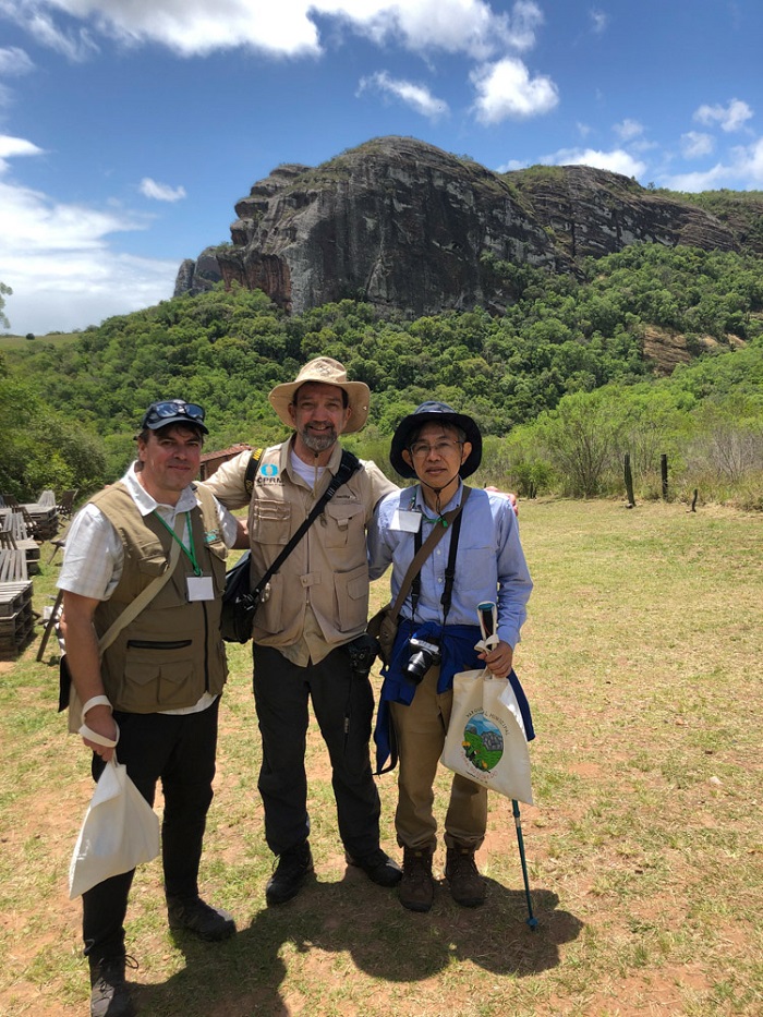 Marcelo Goffermann, representante do SGB na missão, acompanhado dos avaliadores Antônio Matencio e Mahito Watanabe, com a Pedra do Segredo ao fundo